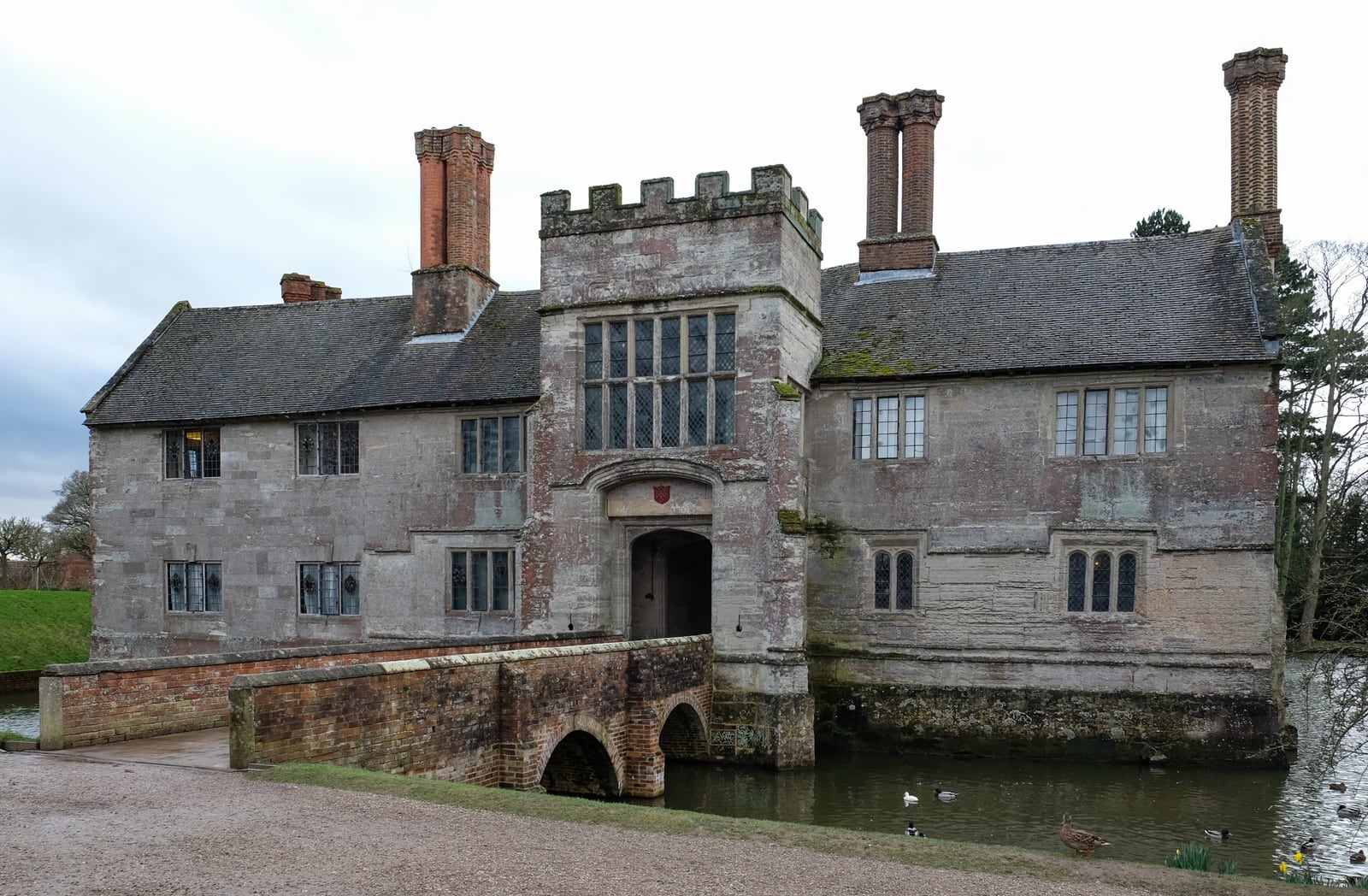 Baddesley Clinton, a moated manor house in Warwickshire, seen across the moat with its gatehouse tower.