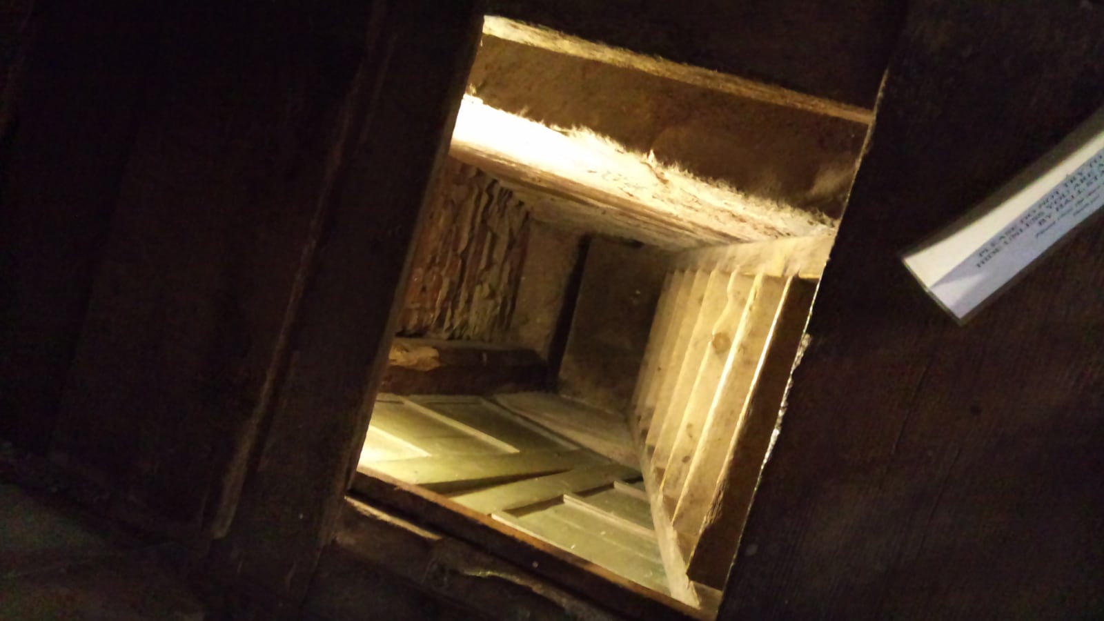 An opened panel in the Withdrawing Room at Harvington Hall revealing the narrow shaft of a priest hole.